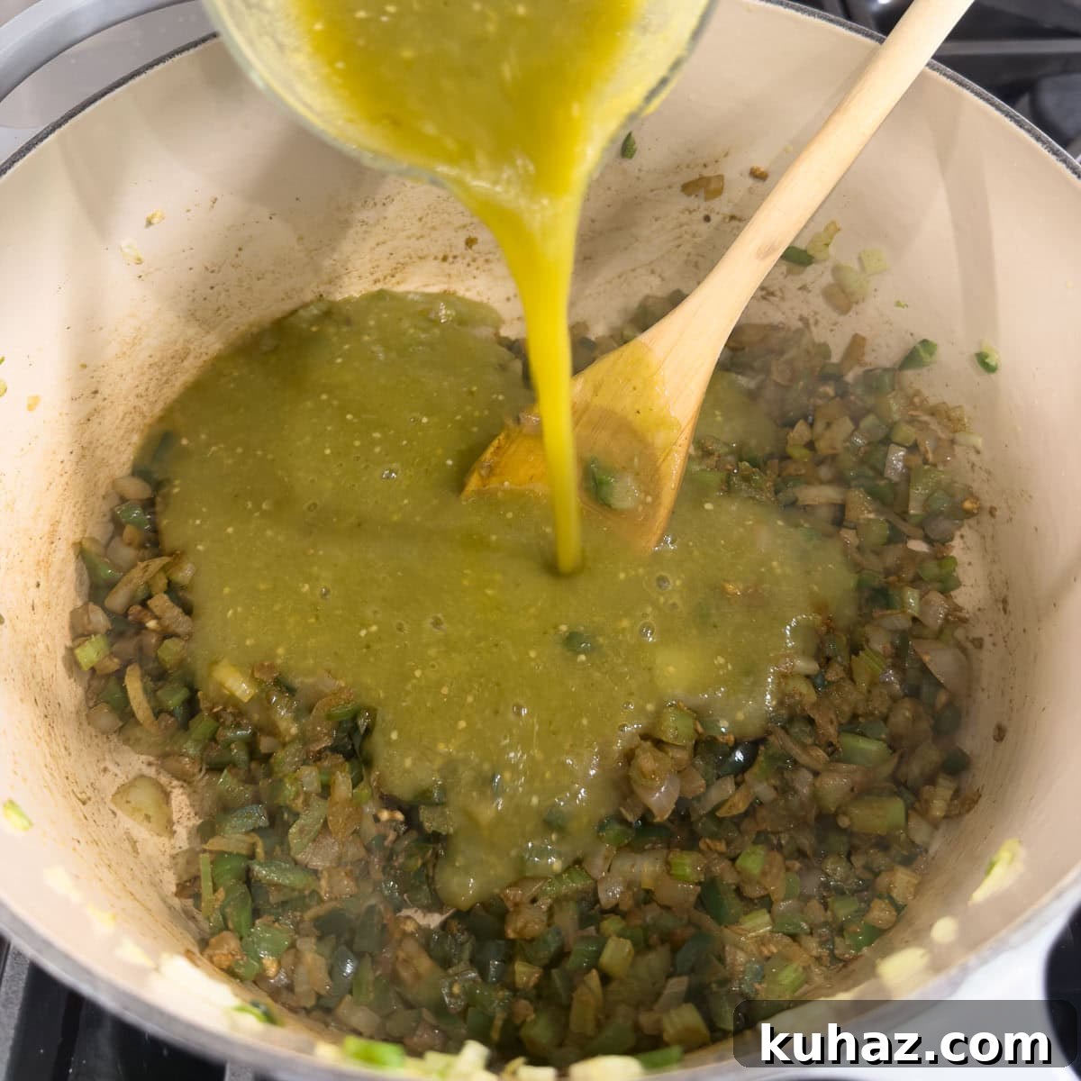 Zesty Tomatillo Soup Recipe with Chicken or Turkey 7 Adding tomatillo sauce to a pot of sautéd vegetables, with a wooden spoon.
