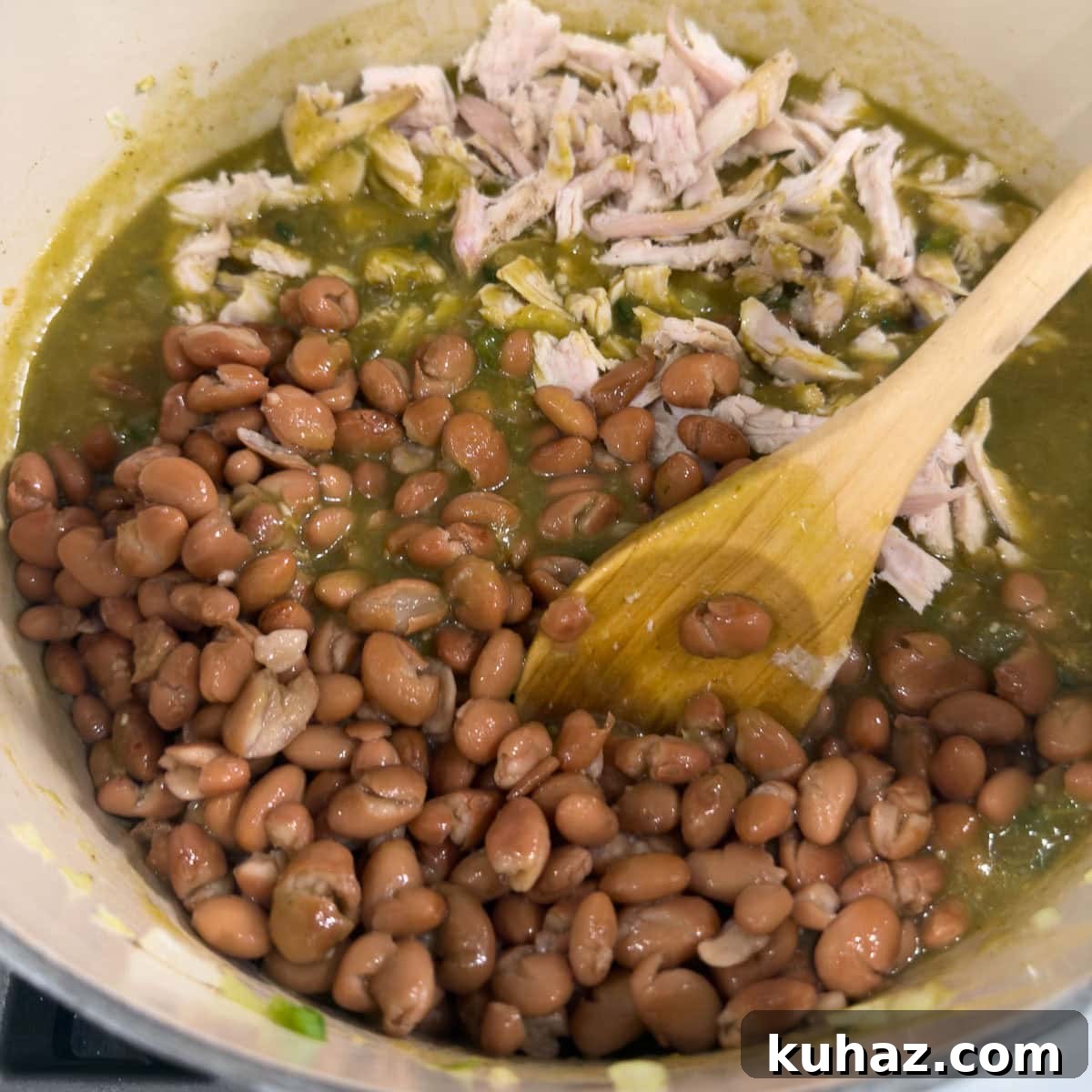 Zesty Tomatillo Soup Recipe with Chicken or Turkey 8 Adding shredded chicken and pinto beans to a soup pot making tomatillo soup.