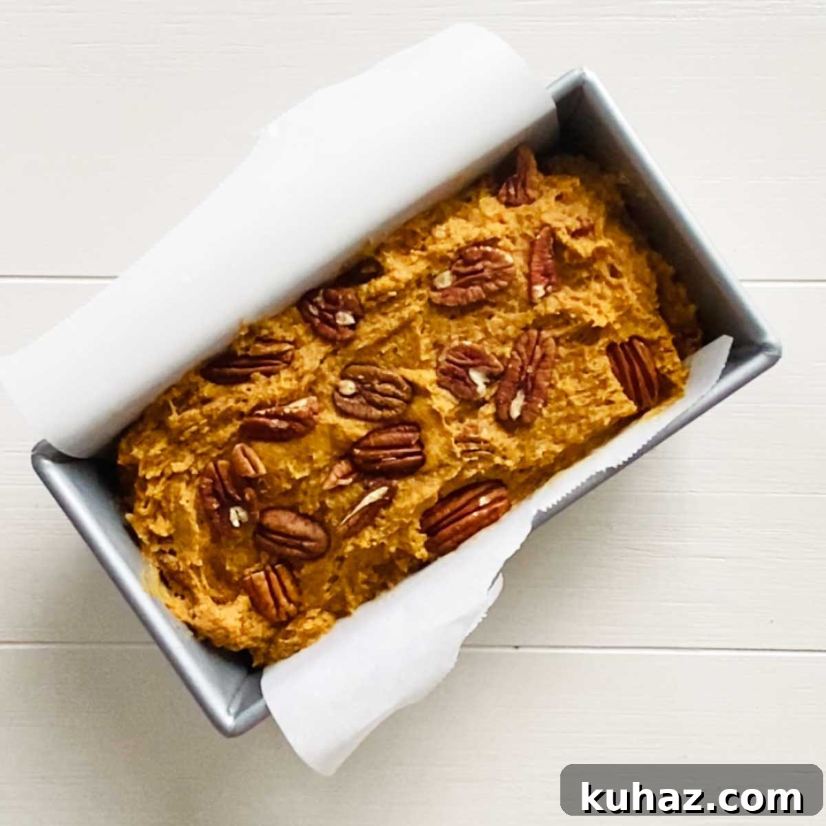 Pecan halves on top of pumpkin bread batter
