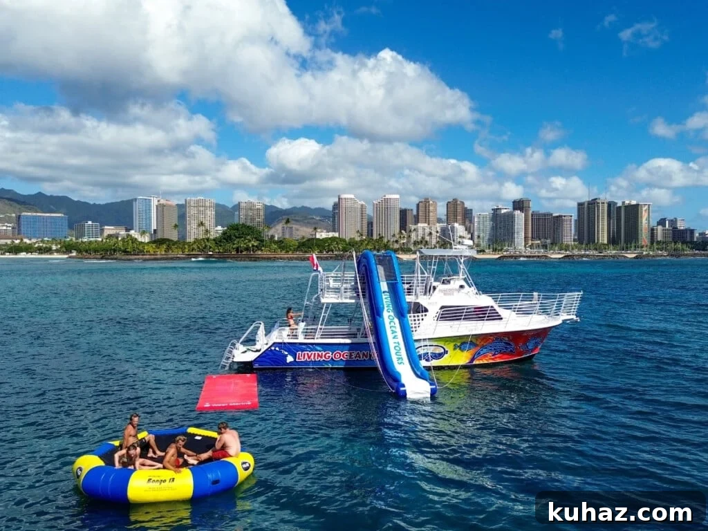 A recreational boat with waterslide and floating platform anchored off Waikīkī with city skyline and greenery in the background.