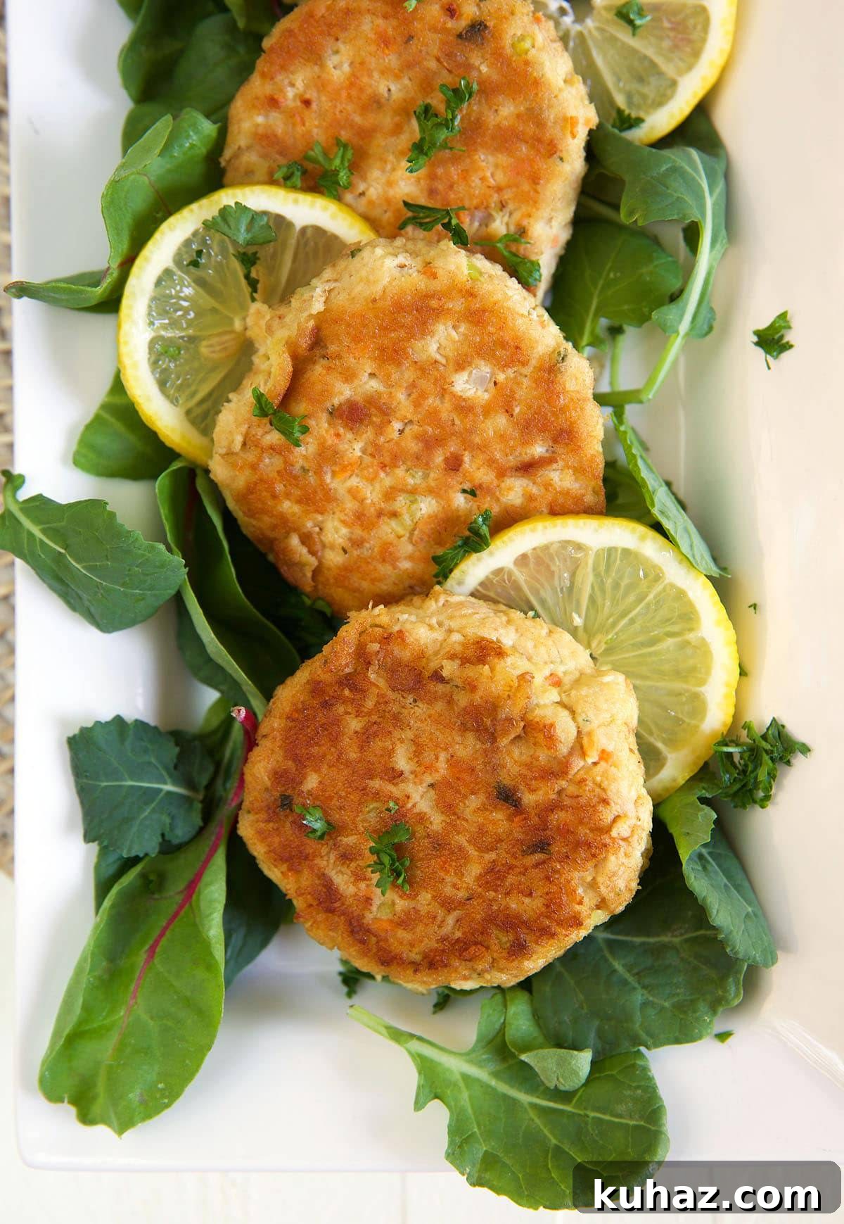 Tuna patties are placed on a plate next to lemon slices and leafy greens.