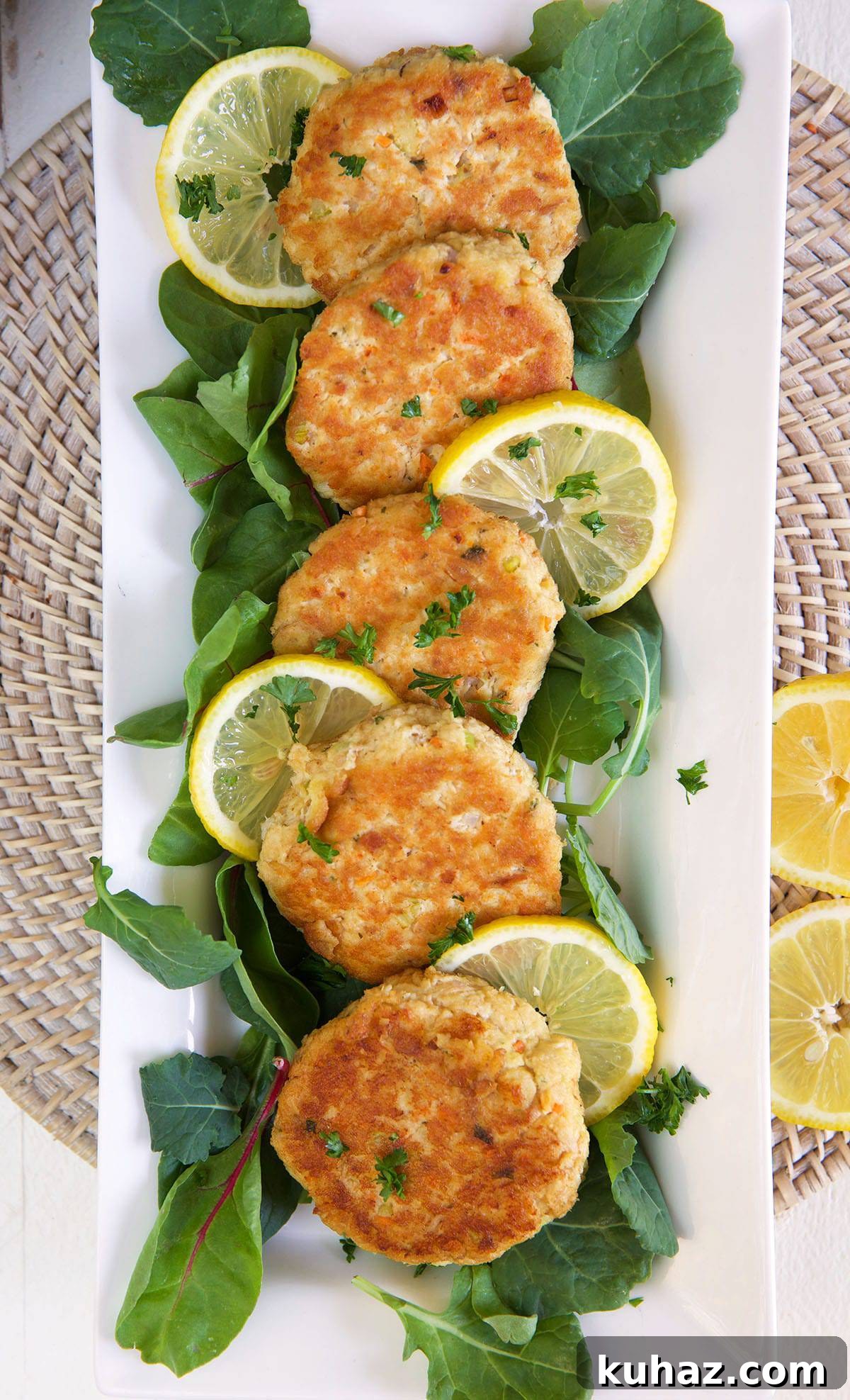 Five tuna patties are lined up on a long white serving plate.