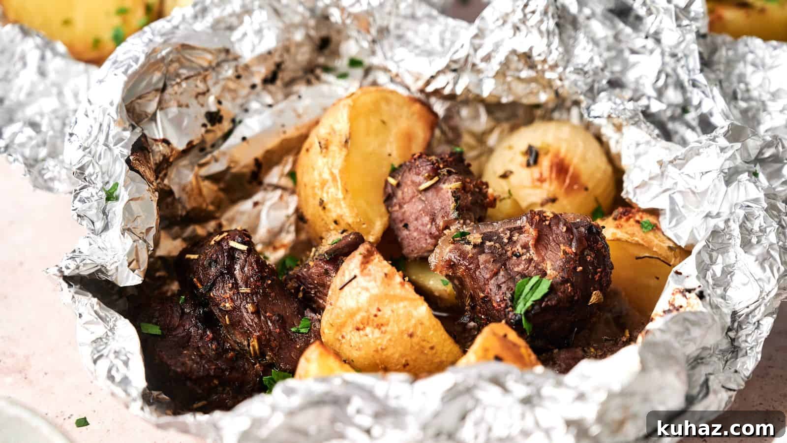 19 BBQ Dinner Recipes That Made Dad Stop Asking What's Next 12 Chunks of cooked beef and roasted potatoes served in an open aluminum foil packet, garnished with herbs.