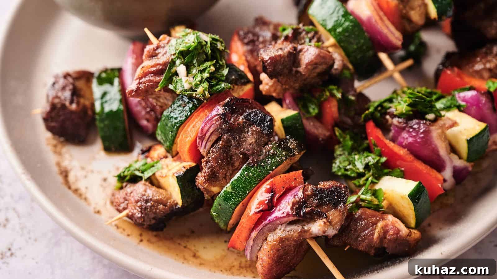 19 BBQ Dinner Recipes That Made Dad Stop Asking What's Next 21 Grilled meat and vegetable skewers with zucchini, red onion, and red bell pepper, garnished with chopped herbs, served on a beige plate.