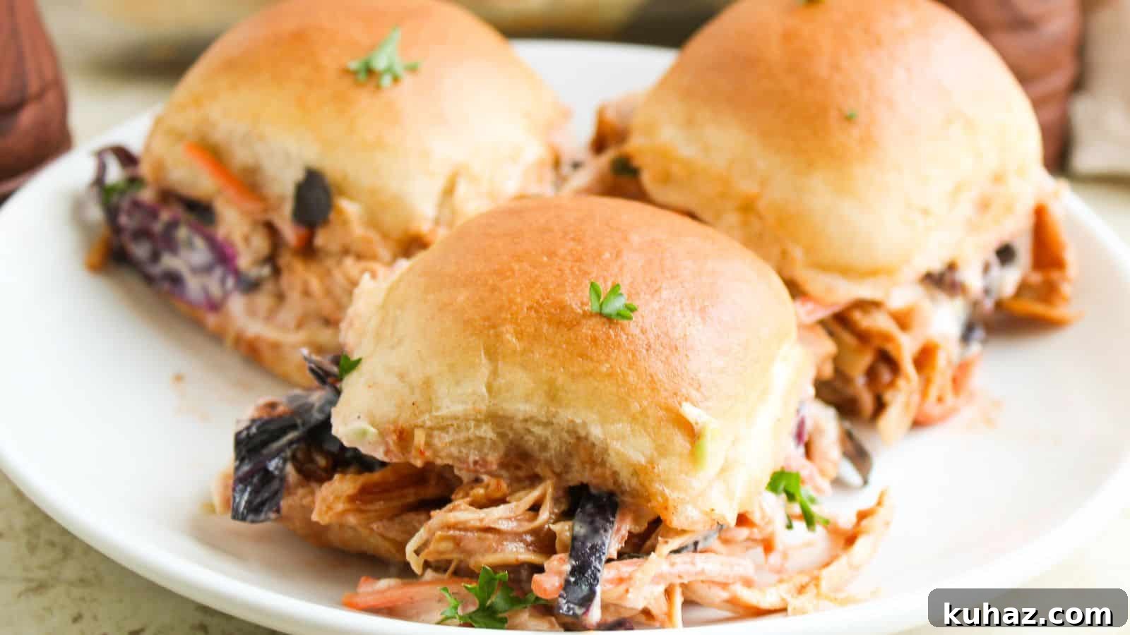 19 BBQ Dinner Recipes That Made Dad Stop Asking What's Next 4 Three pulled pork sliders with coleslaw on a white plate, topped with a sprig of parsley.