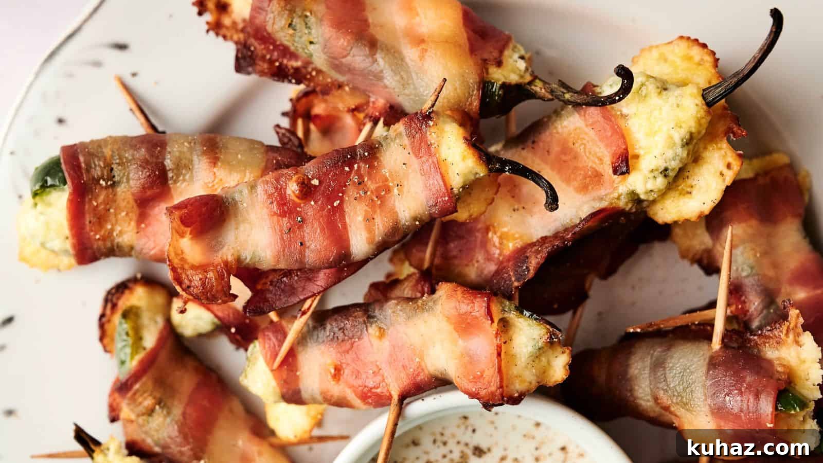 19 BBQ Dinner Recipes That Made Dad Stop Asking What's Next 5 A plate of bacon-wrapped jalapeño poppers filled with cheese, secured with toothpicks, next to a small dish of dipping sauce.