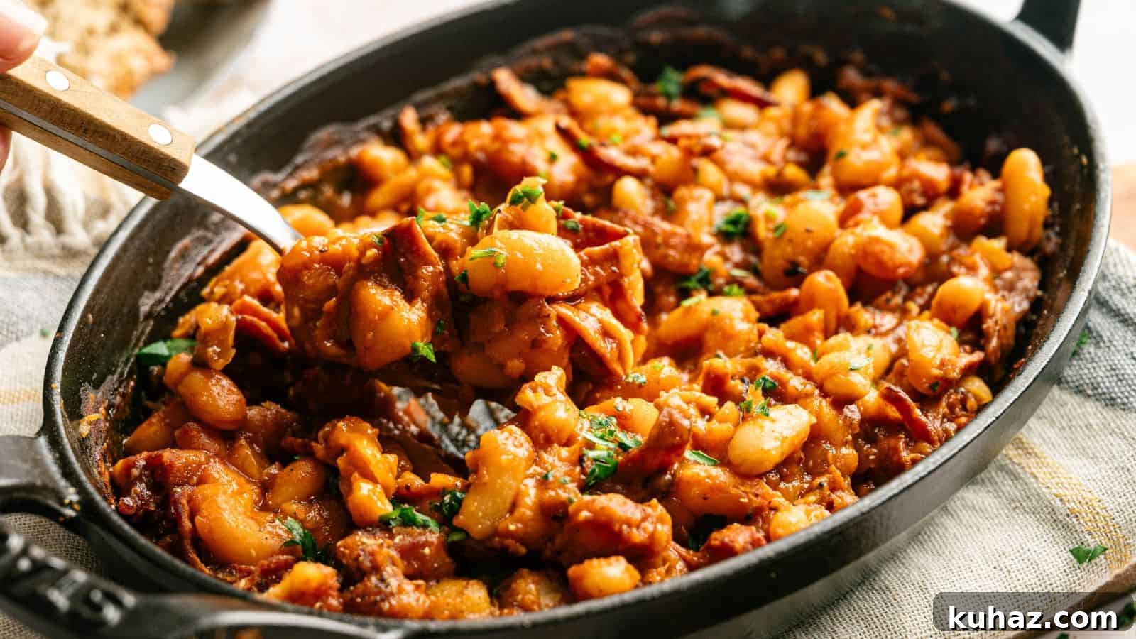 19 BBQ Dinner Recipes That Made Dad Stop Asking What's Next 7 A black oval dish filled with baked beans in a rich sauce, mixed with pieces of bacon and garnished with chopped parsley.