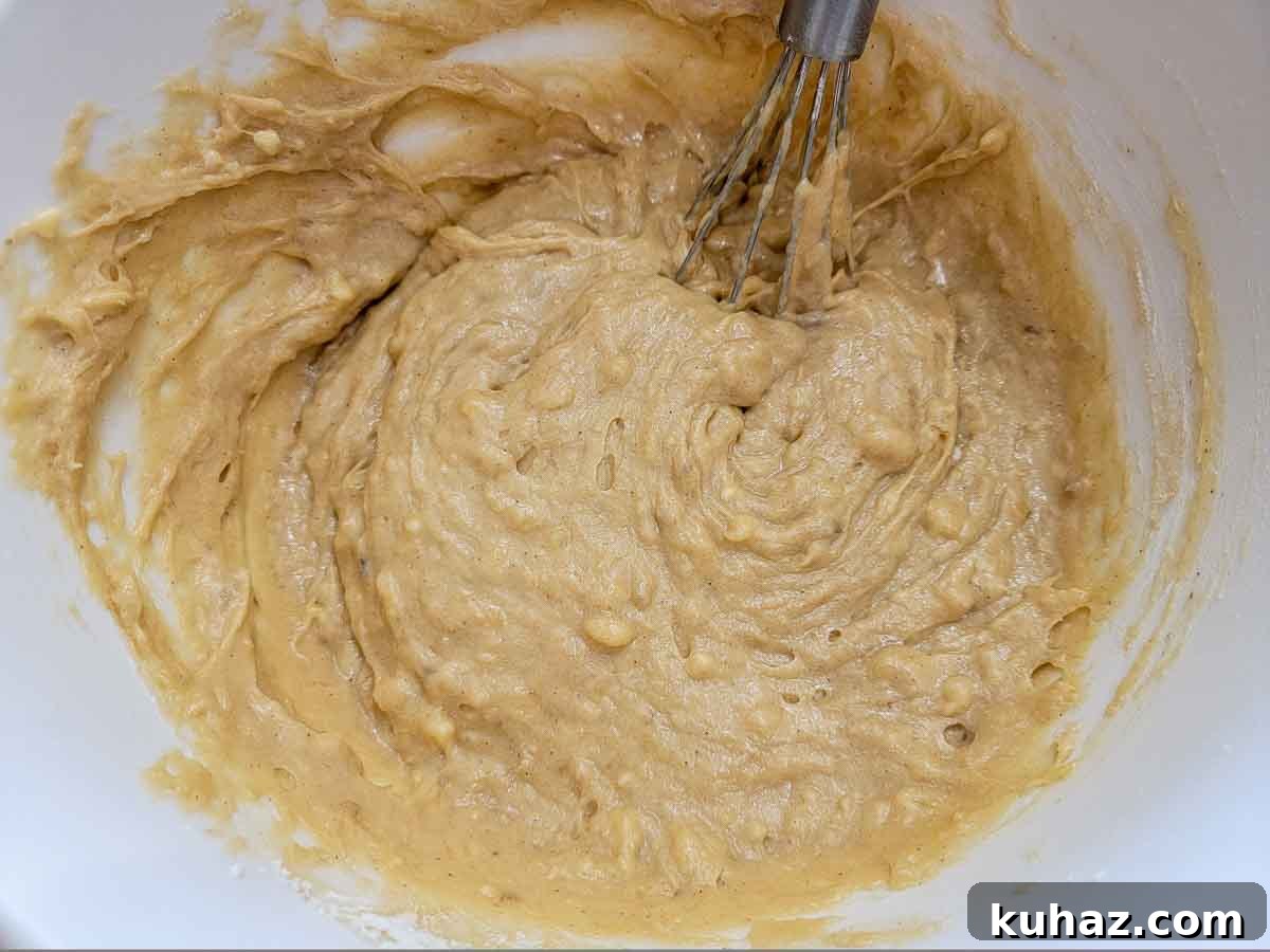 Maui Banana Bread Recipe with Coconut and Macadamia Nuts 4 banana bread batter whisked in a bowl.