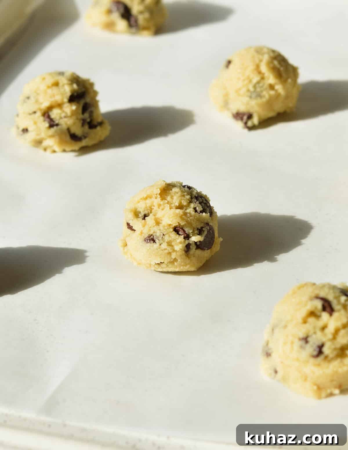 Soft and Chewy Almond Flour Chocolate Chip Cookie Recipe 8 cookie dough balls on a sheet pan.
