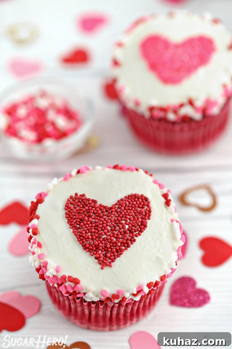 White cupcake with heart sprinkles around the edge and a heart-shaped sprinkle shape in the center