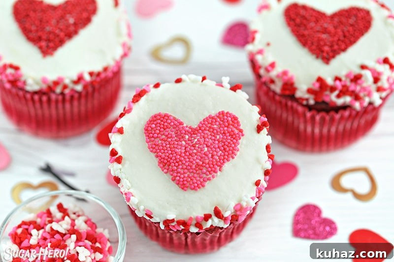 White cupcake with a pink heart-shaped sprinkle shape in the center