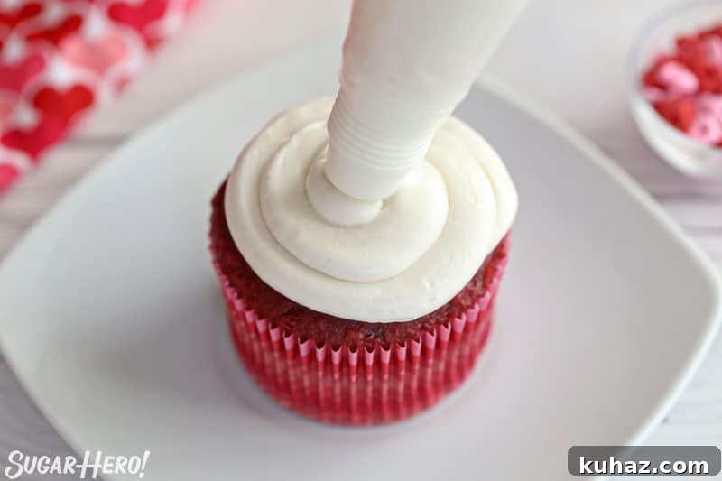 Red velvet cupcake being frosted with white buttercream