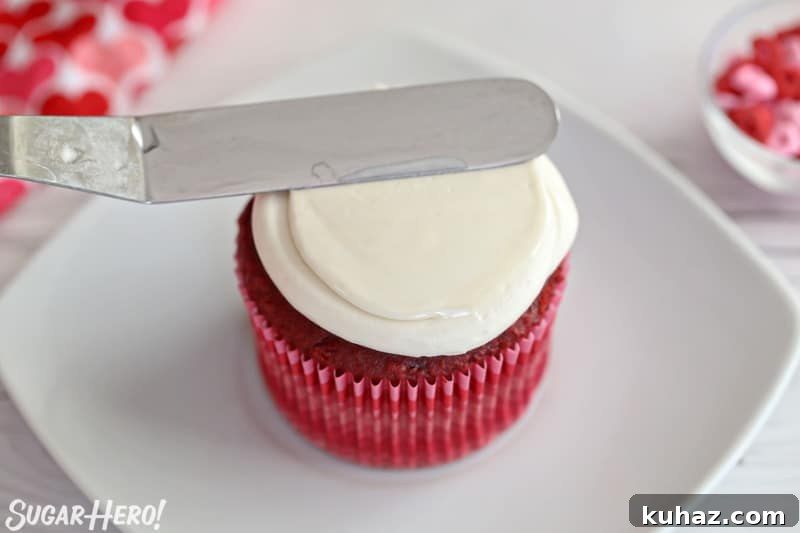 Small spatula smoothing the top of a cupcake with white buttercream