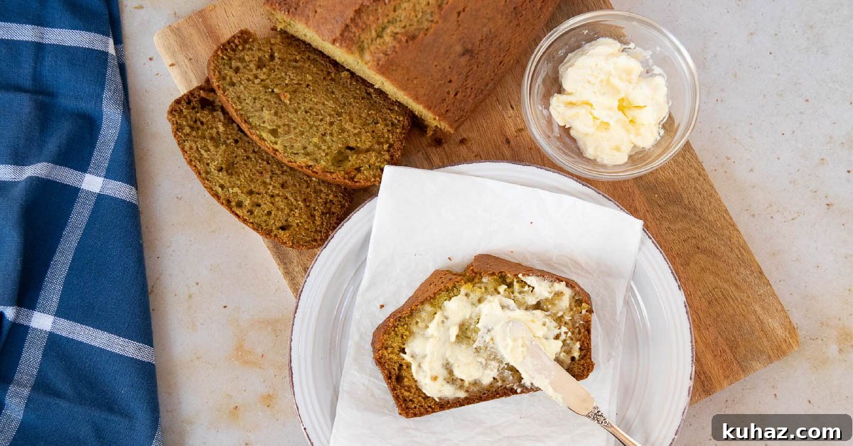 Moist Zucchini Bread Recipe 2 Overhead shot of a loaf of zucchini bread with a slice being spread with clotted cream