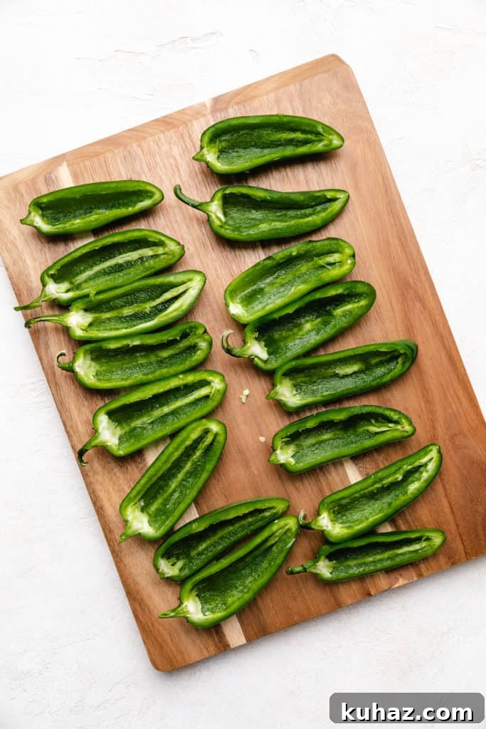 Crispy Oven-Baked Jalapeno Poppers with Cream Cheese 3 Deseeded jalapeños on a cutting board.