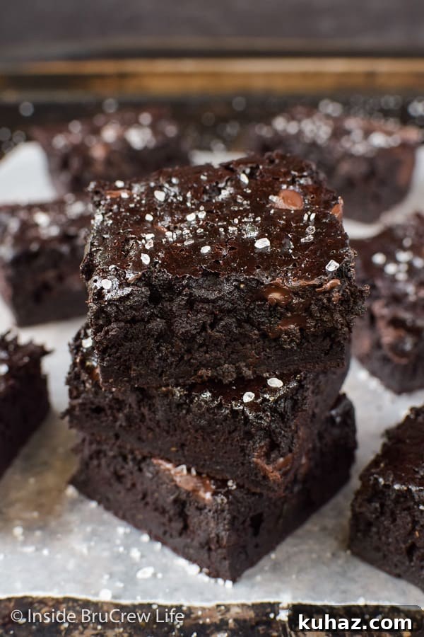 Fudgy Dark Chocolate Zucchini Brownies - dark chocolate and shredded zucchini come together in these amazing fudgy brownies. Try this easy recipe and see how good they really are! Three chocolate zucchini brownies stacked together with more brownies all around it
