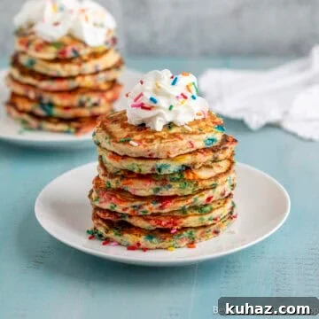 A stack of confetti pancakes topped with a dollop of whipped cream.