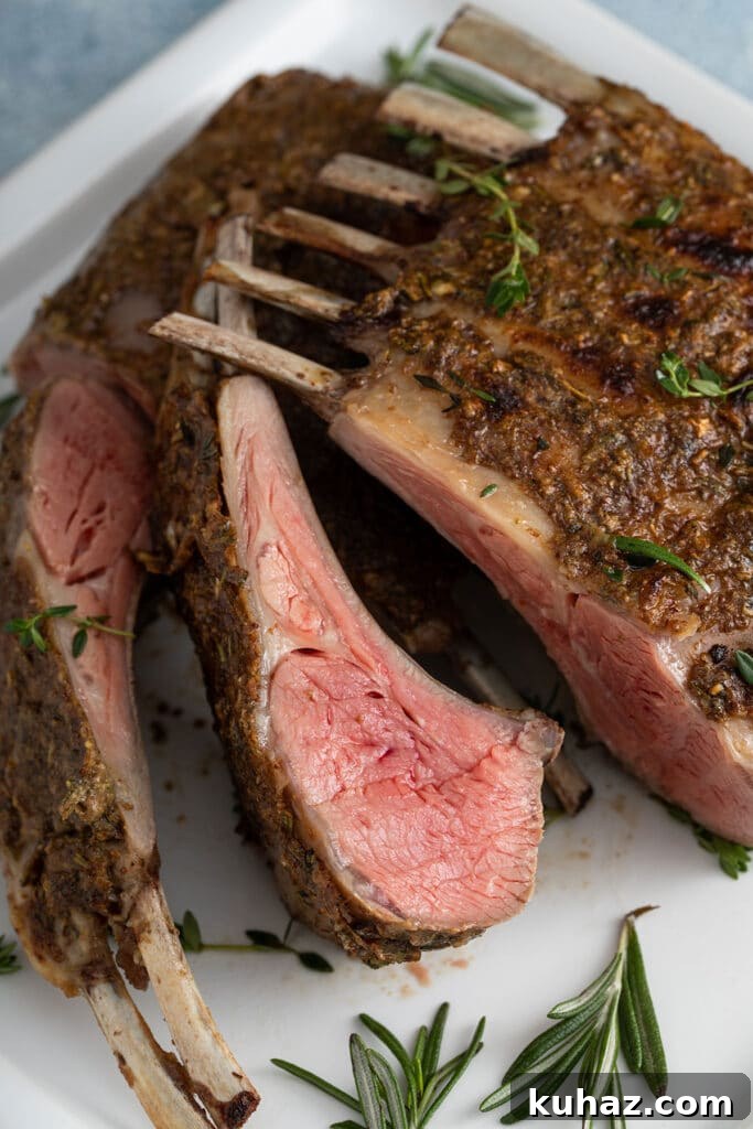 Lamb rack and lamb chops cooked to medium rare on a white plate.