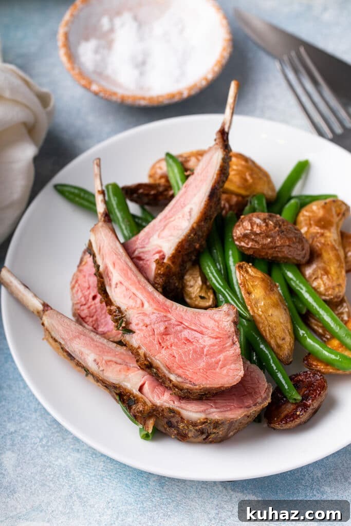 Pink medium-rare lamb ribs from a lamb rack served with roasted potatoes and green beans.