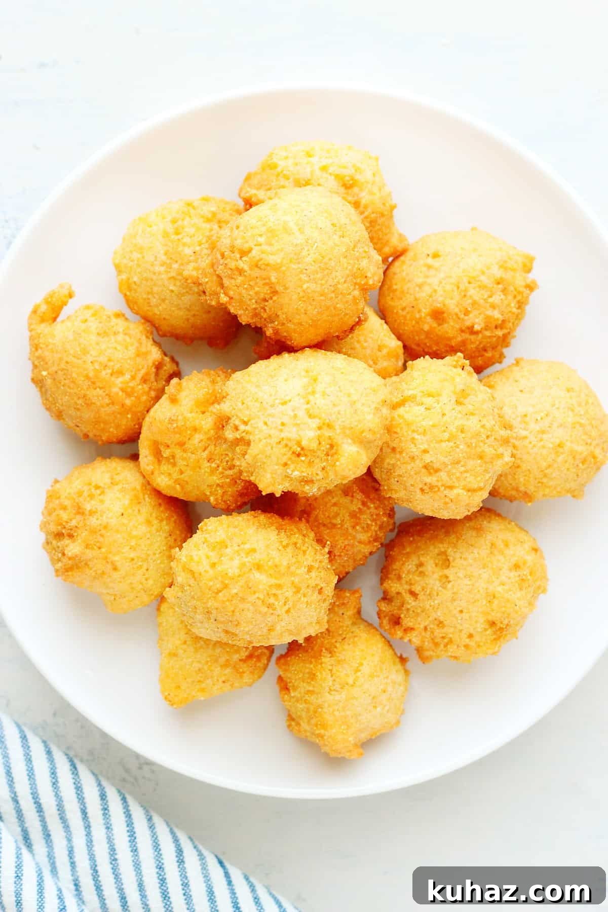 Homemade Hush Puppies Hush puppies on a plate on a board.