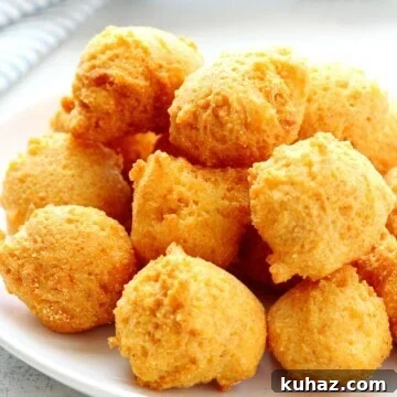 Southern Hush Puppies Recipe with Crispy Cornmeal Batter 3 Fried hush puppies on a white plate.