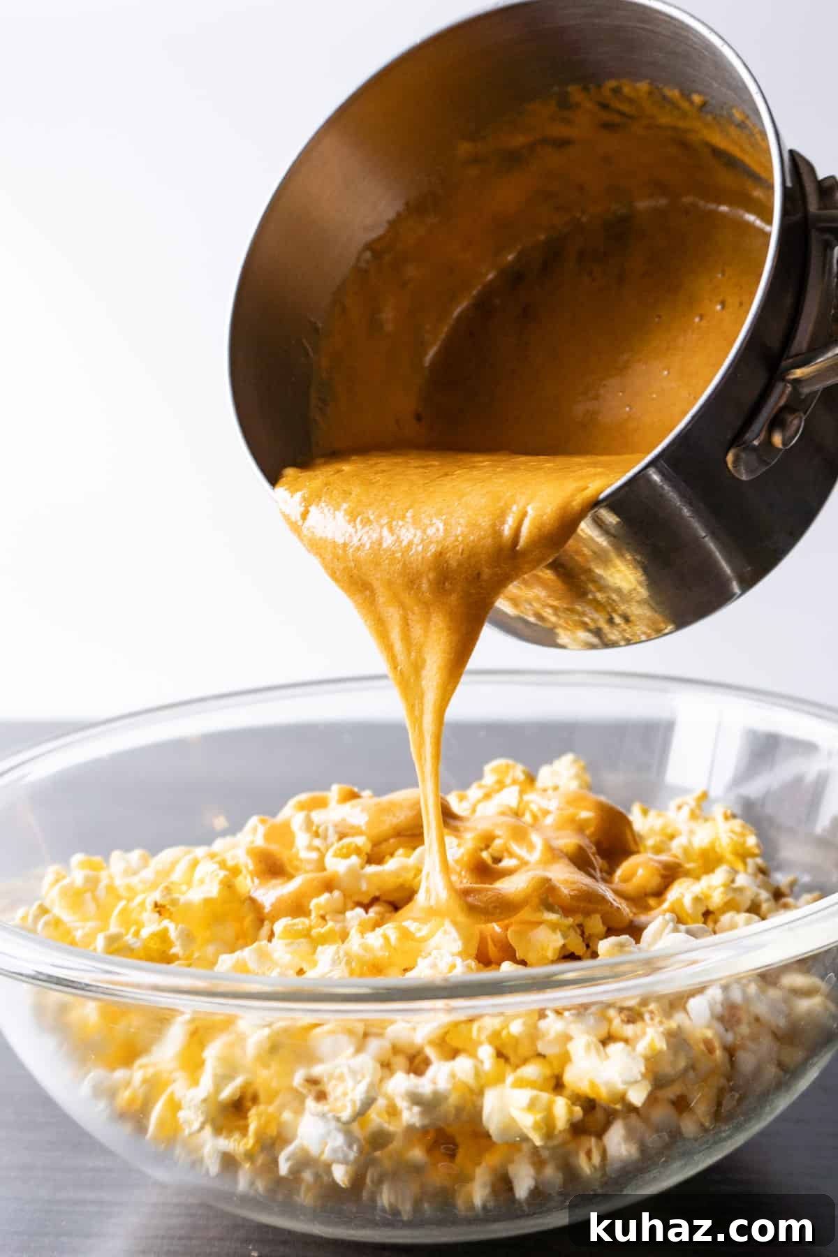 Spicy Buffalo Popcorn Recipe 4 pouring caramel over popcorn in a bowl