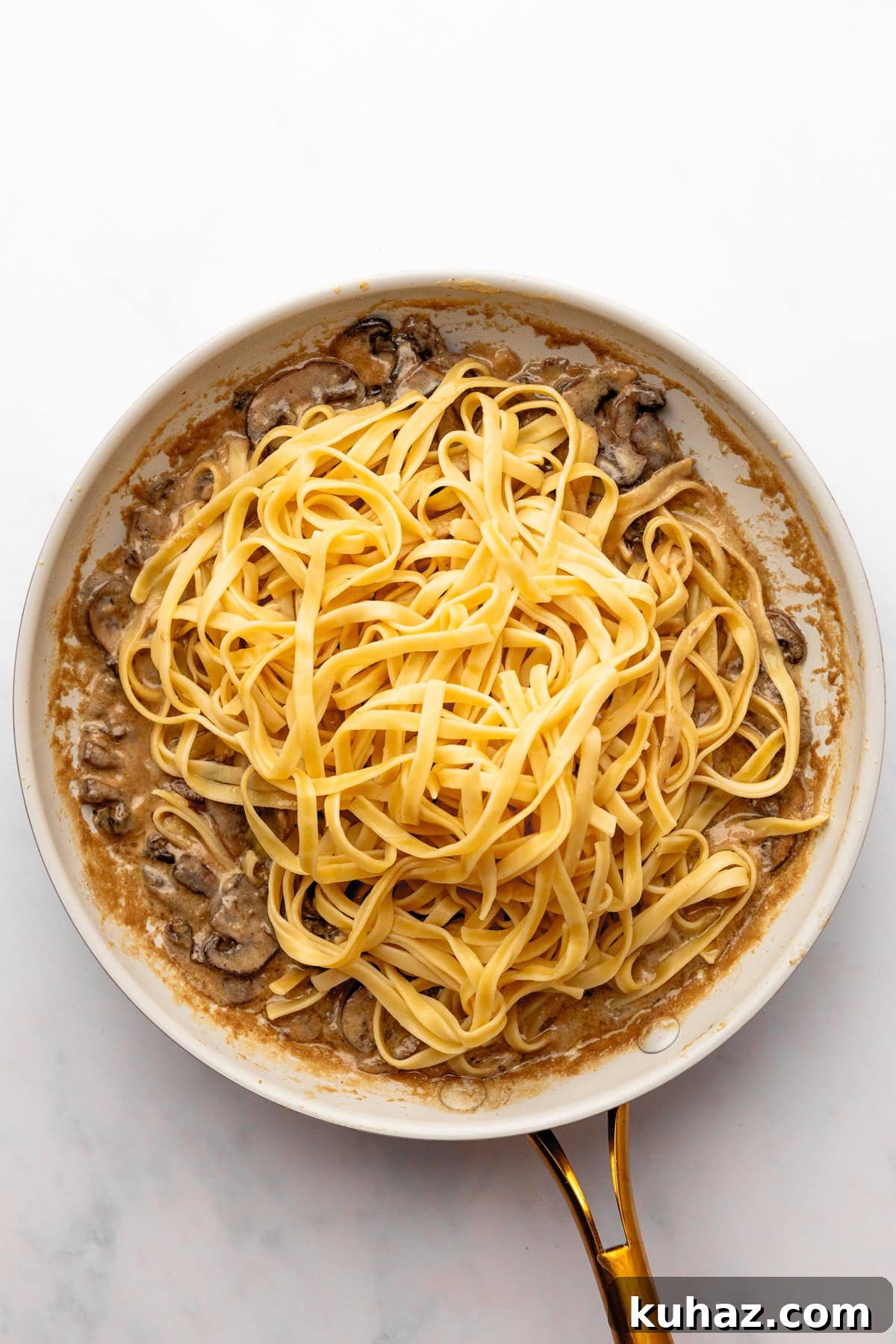 Creamy Mushroom Pasta with Garlic and Parmesan 7 An overhead image of adding pasta to the sauce.