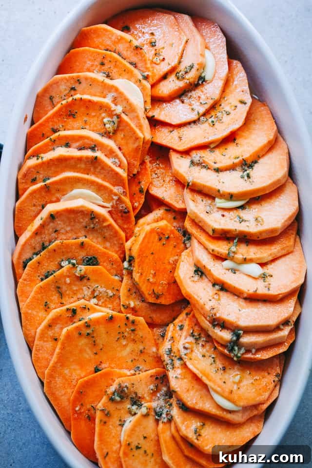 Fanned-out sweet potato slices arranged in a baking dish and topped with seasonings.