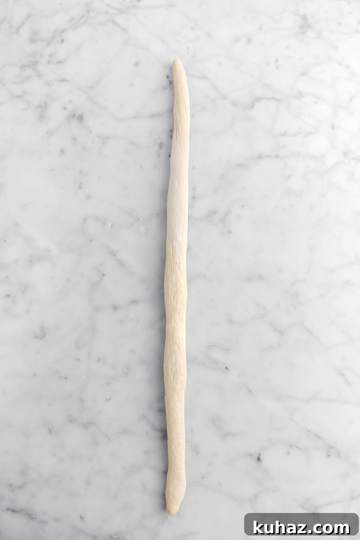 Giant Goat Cheese Stuffed Soft Pretzels 16 dough rolled out to a long rope on marble surface.