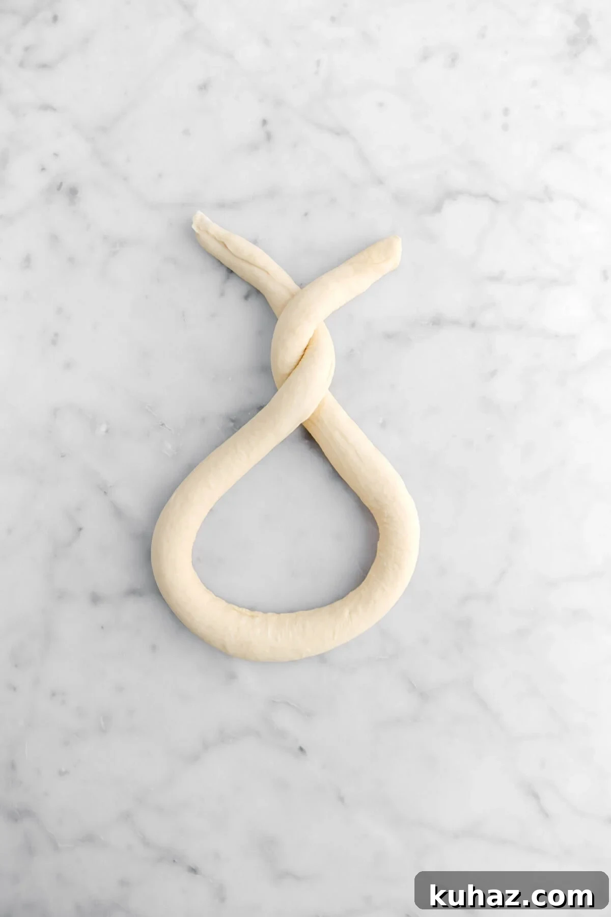 Giant Goat Cheese Stuffed Soft Pretzels 18 dough twisted on marble surface.