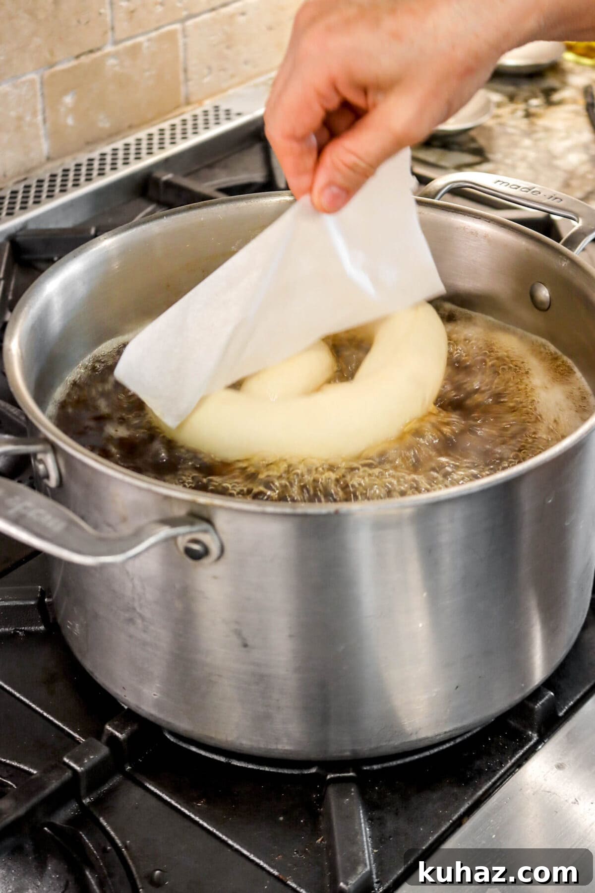 Giant Goat Cheese Stuffed Soft Pretzels 21 pretzel peeling off of parchment into pot of boiling water.