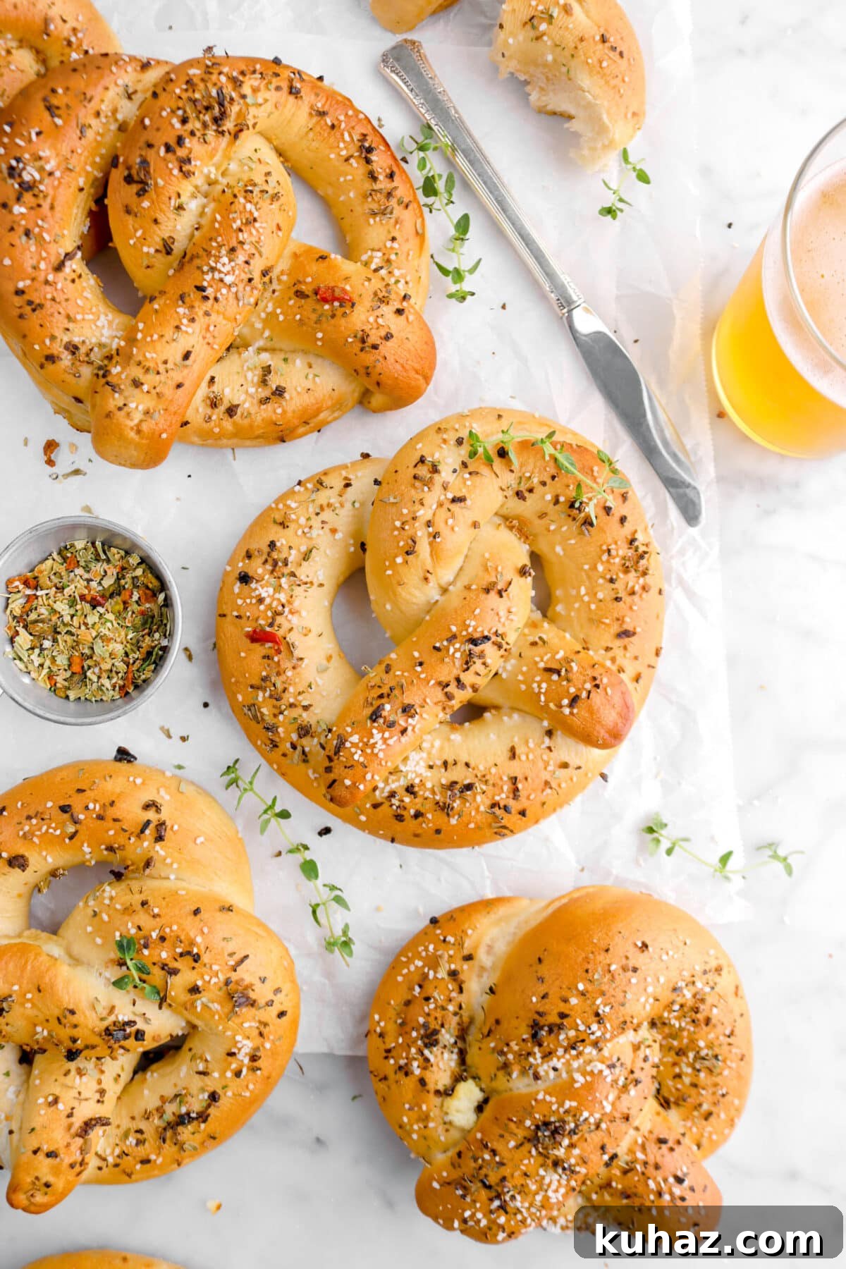Giant Goat Cheese Stuffed Soft Pretzels 5 close up of four pretzels with measuring cup of dried herbs beside, glass of beer, a knife, and thyme sprigs around.