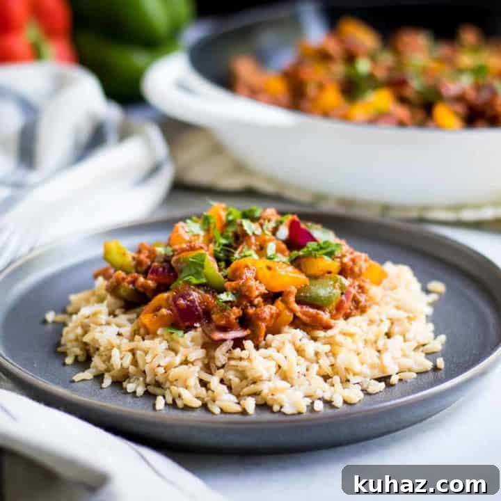 Skillet dinner on top of rice on a gray plate on white counter.