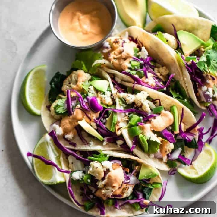 Healthy Tacos on a white plate on a white counter with sauce and limes on it.