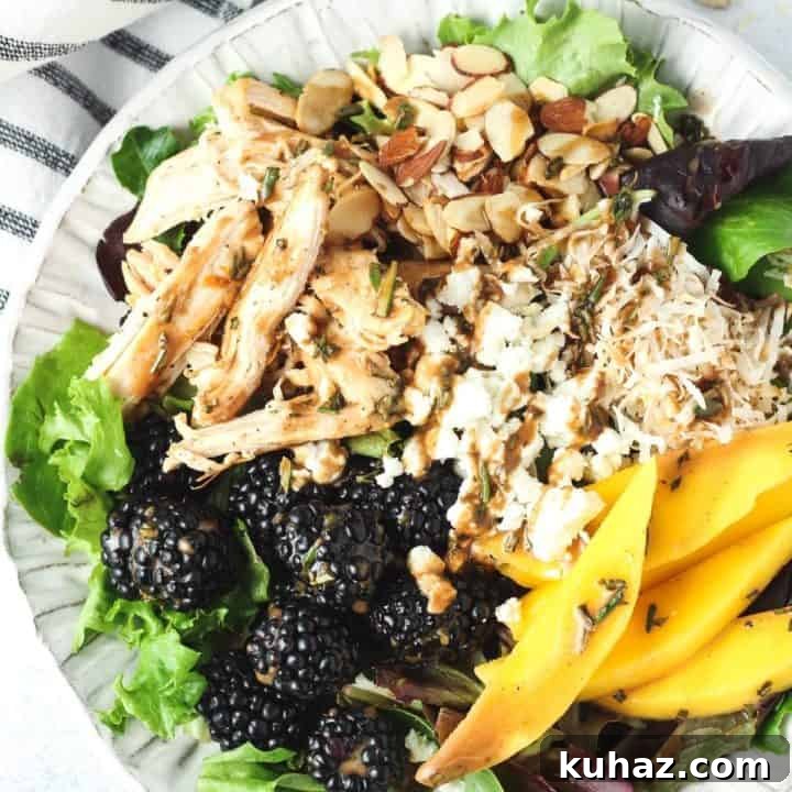 Healthy mango salad in a white bowl on a white counter with striped towel next to it.