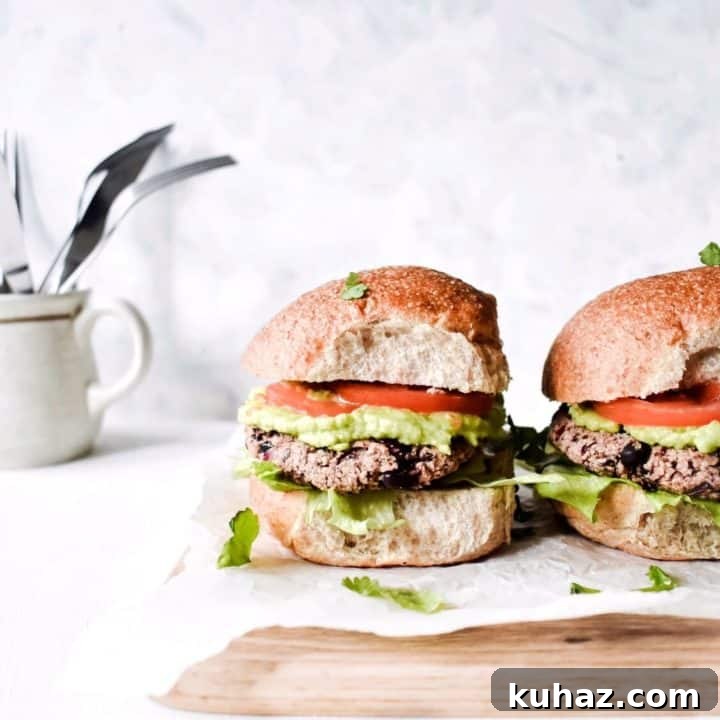 Vegan black bean burgers on white paper on a wooden cutting board with a white background.