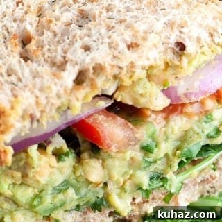 Close up shot of vegan sandwich showing avocado, tomato, and red onion.