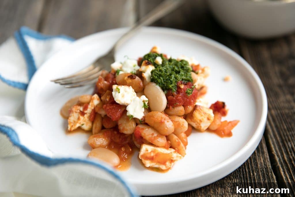 Vegetarian Baked Tomato Beans with Tangy Feta 5 A portion of baked white beans and tomatoes with feta on a plate.