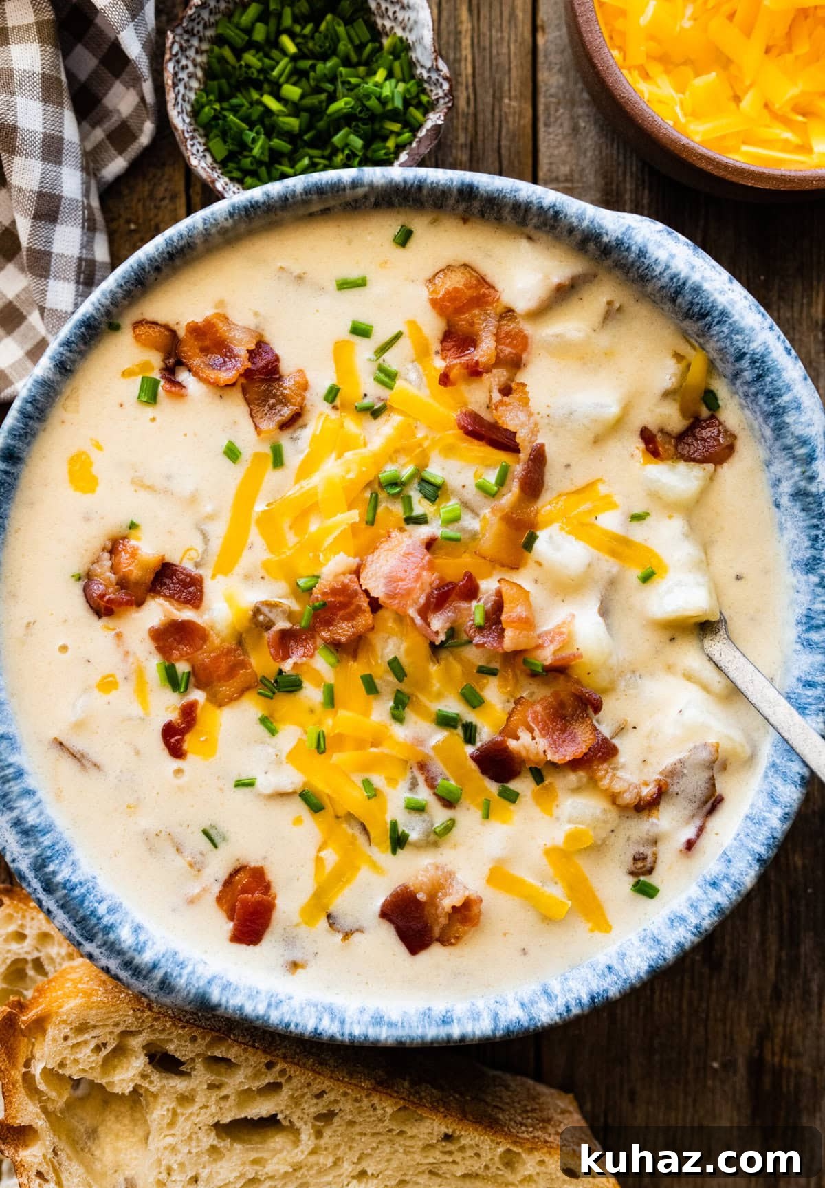 Outback Steakhouse Baked Potato Soup Copycat Recipe 2 Spoon in a blue bowl of baked potato soup topped with cheese and bacon.