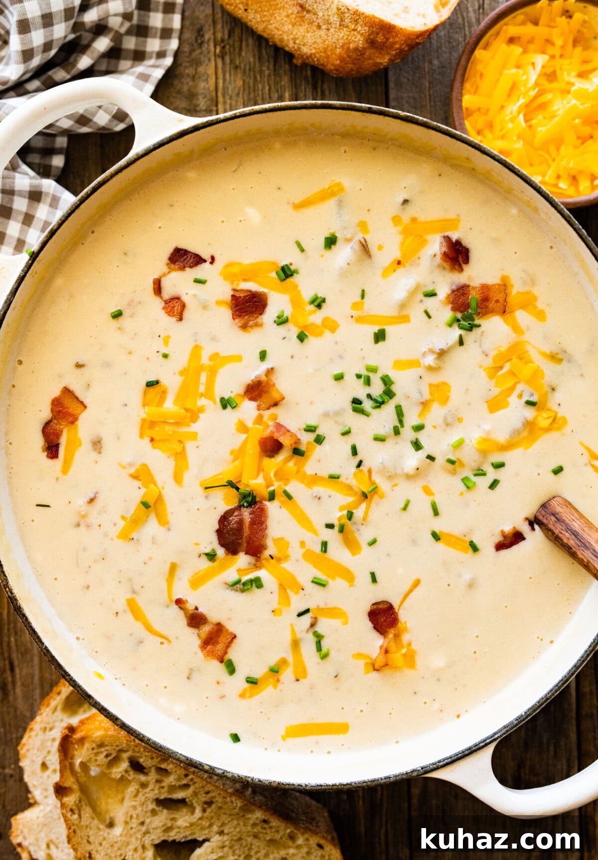 Outback Steakhouse Baked Potato Soup Copycat Recipe 13 Wooden spoon in a Dutch oven of baked potato soup topped with cheese and bacon.