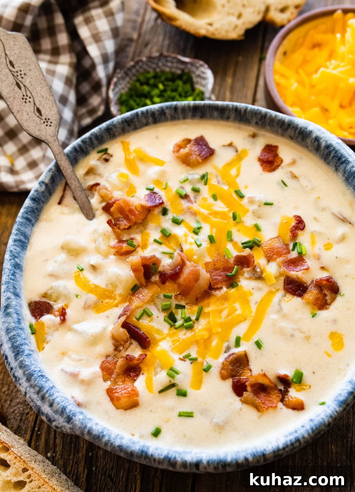 Outback Steakhouse Baked Potato Soup Copycat Recipe 14 Spoon in a blue-rimmed bowl of Outback baked potato soup topped with cheese and bacon bits.