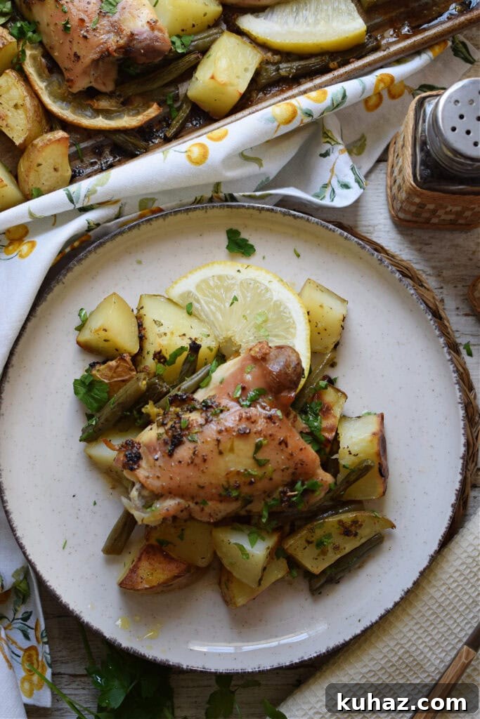 Sheet Pan Lemon Herb Chicken with Roasted Vegetables 11 Lemon chicken on a plate with potatoes.