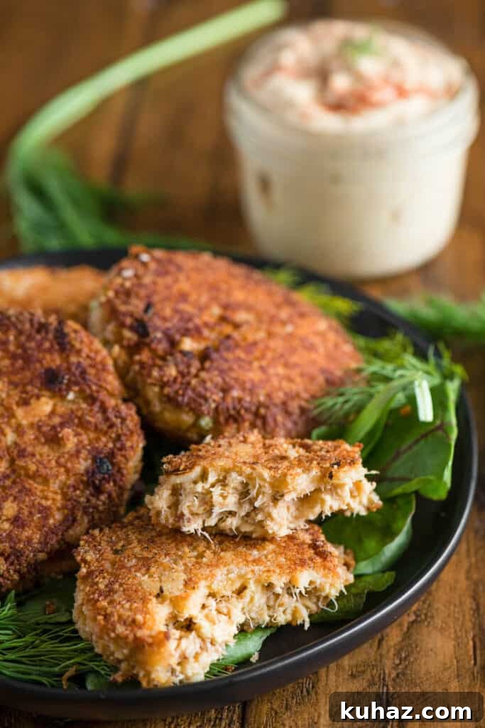 homemade crab cakes on platter with remoulade sauce in the background.