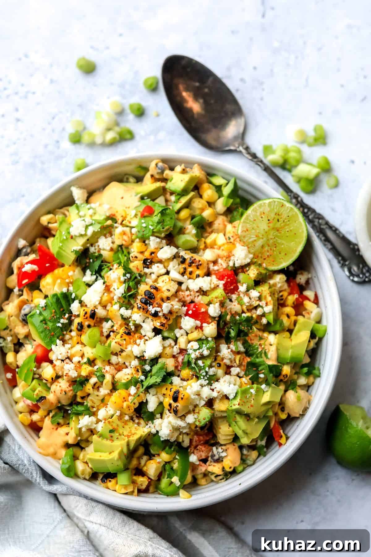 Mexican Street Corn Pasta Salad in a white ceramic bowl with a spicy lime on top.
