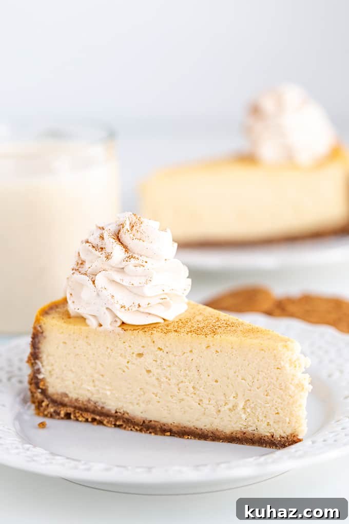 Creamy Eggnog Cheesecake Recipe for the Holidays 2 slice of eggnog cheesecake on a white plate with a glass of eggnog and gingersnap cookies behind the plate