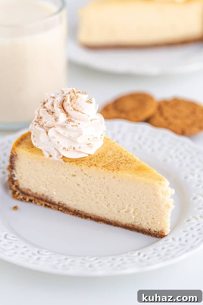 Creamy Eggnog Cheesecake Recipe for the Holidays 5 slice of cheesecake on a white lace plate with cookies and eggnog behind the cheesecake on a white surface