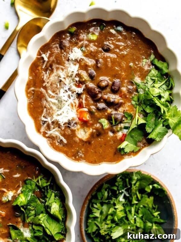 White ceramic bowl with Panera Black Bean Soup Recipe in the bowl with two spoons to the side.
