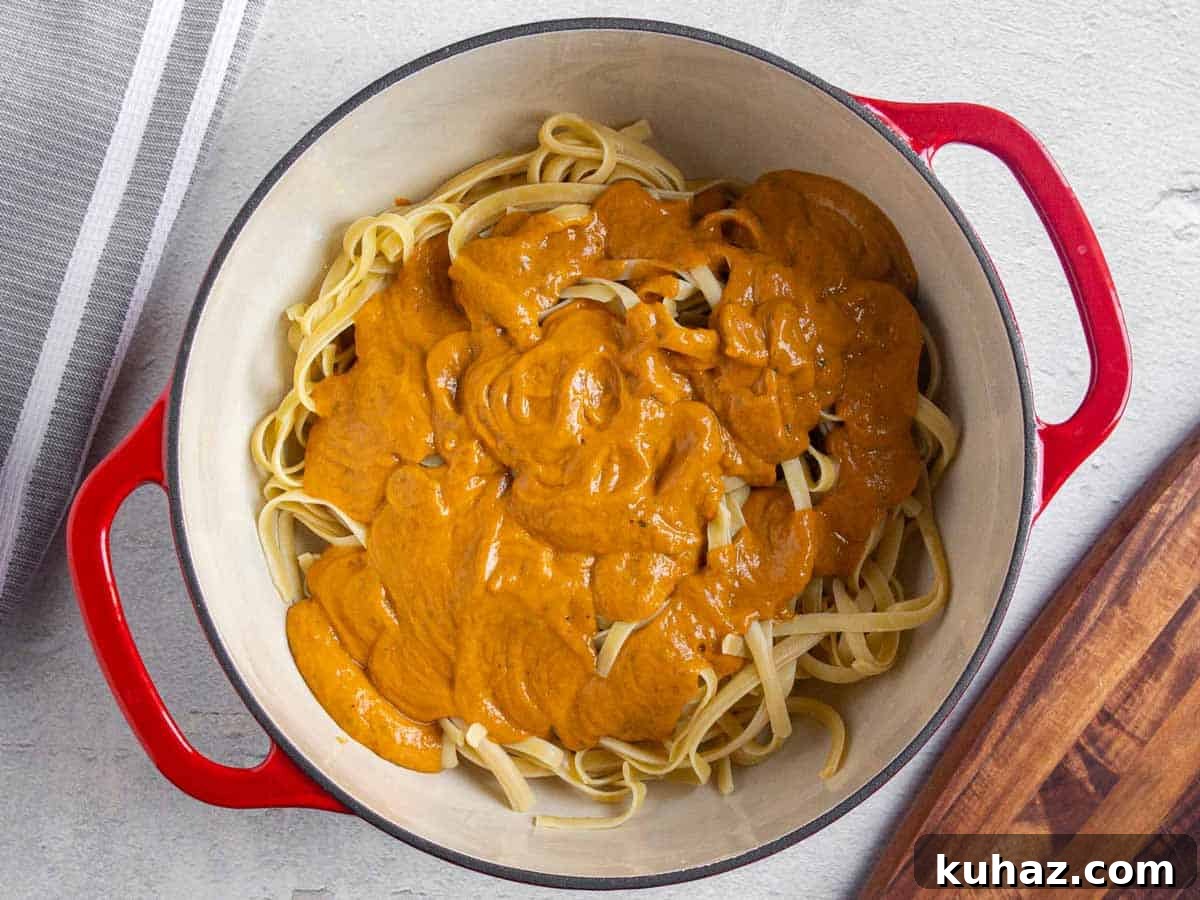 Creamy Avocado Bell Pepper Pasta 7 Avocado bell pepper sauce poured over fettuccine noodles in a large pot.
