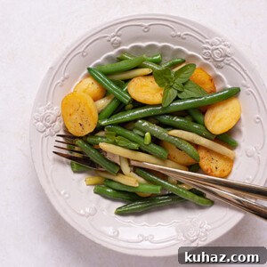 Overhead view of Green Beans with Crispy Potatoes on a decorative white plate on a white table