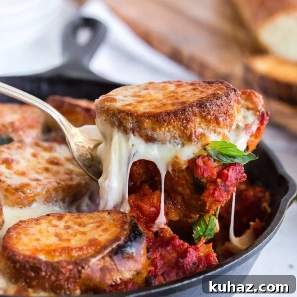 Baked Meatballs in Marinara with Melted Mozzarella 8 Scooping a portion of meatballs and bread out of skillet with melted cheese.